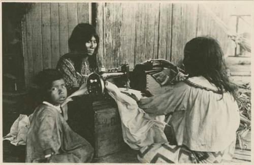 Two women and a child with a sewing machine