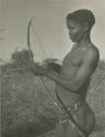 "/Qui Hunter" holding a bow and arrow, showing method of holding and releasing (print is a cropped image)