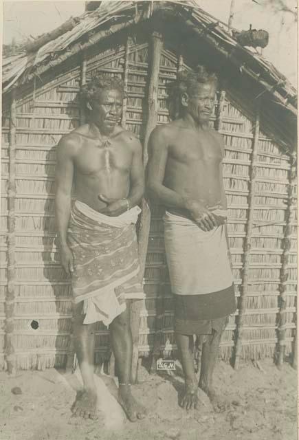 Two men standing in front of a structure