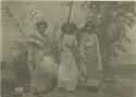 Three women standing in front of a tree or bush