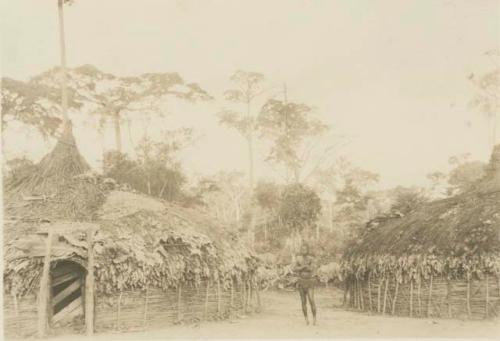 Man standing between two huts