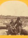 Two people seated on logs