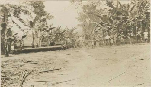 Dragging a dug-out canoe through a village en route from forest