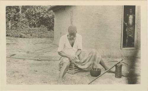 Man rolling strophanthus poison on arrows