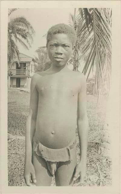 Boy standing, with house in background
