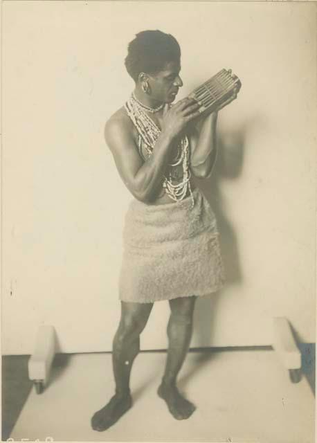 Studio portrait of man standing and holding a musical instrument