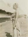 Woman standing, with huts in background