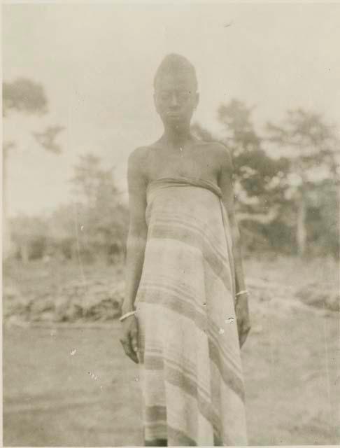 Woman standing, with trees in background