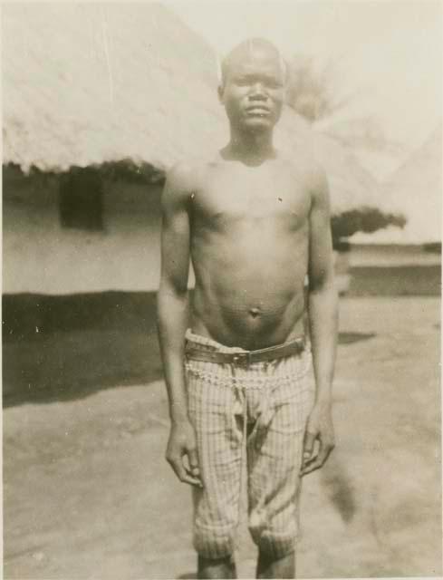 Man standing, with huts in background