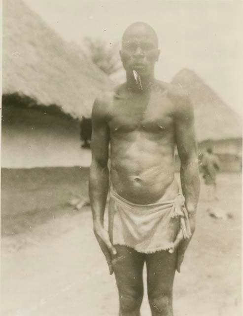 Man standing, with huts in background