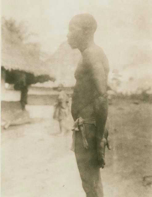 Man standing, with huts in background