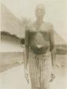 Man standing, with huts in background