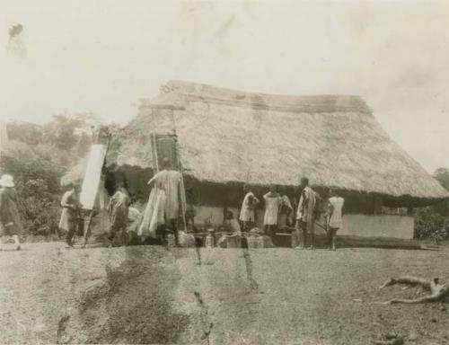 Group of people standing in front of a hut