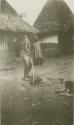 Woman standing on a mat in front of huts