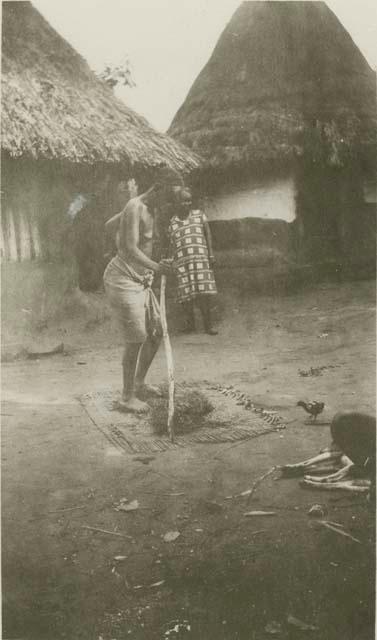 Woman standing on a mat in front of huts