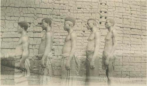 Five men standing in front of a building, side view