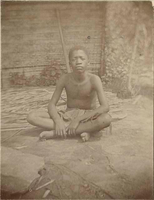 Boy sitting in front of a hut