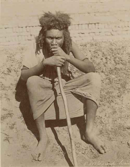 Man sitting and holding a walking stick