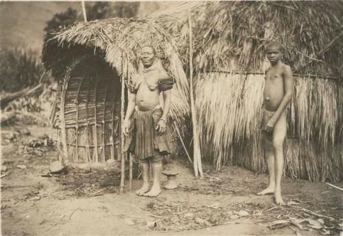 Woman and boy in front of hut