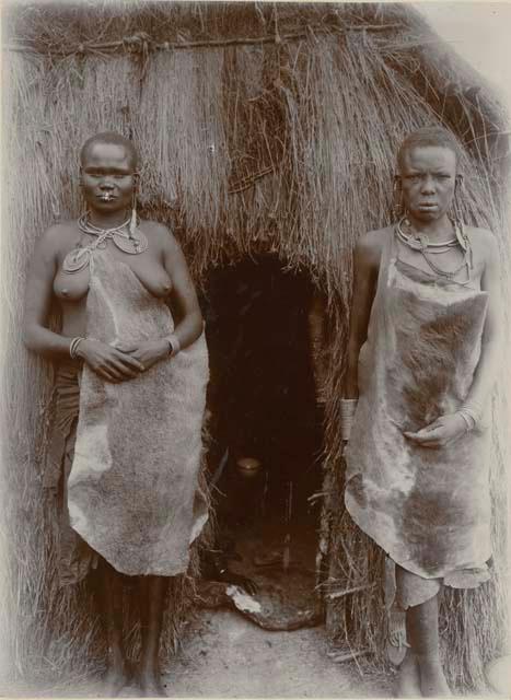 Two women standing in front of a hut