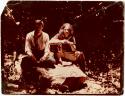 Richard Ross and K'in sitting on a stela in the rainforest