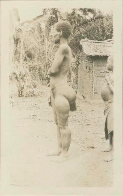 Woman and boy standing in front of a hut