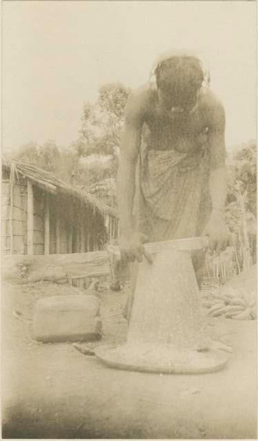 Woman scraping soup stock from a block of wild mango kernel