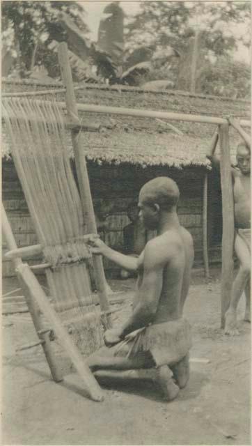 Boy weaving a raffia mat