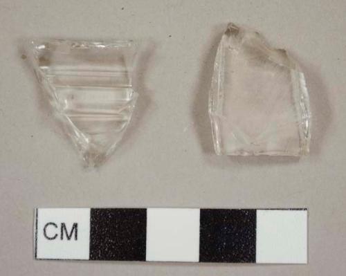 Colorless curved glass fragments, including one fluted tumbler fragment and one with molded ribbing on exterior