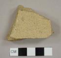 Tan ceramic sherd with black specks, possibly tile fragment