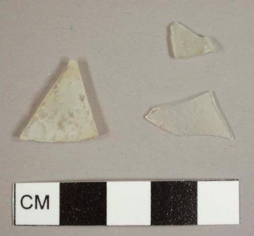 Colorless curved glass fragments, two possibly from a lamp chimney