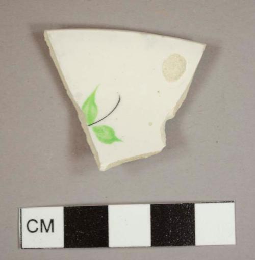 Handpainted pearlware rim sherd from a saucer with green and black floral motif on the interior