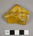 Refined earthenware base sherd of a hollowware vessel with feet and lead or manganese glaze