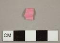 Pink plastic fragment with "[...]DE MILL[...]" embossed on one side