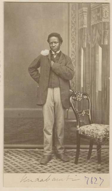 Studio portrait of a man standing next to a chair