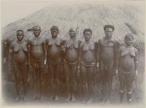 Group of men and women in front of a hut