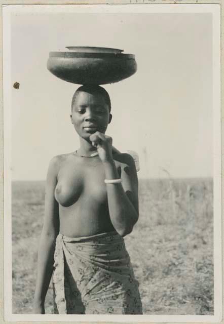 Woman carrying wooden bowl and hoe