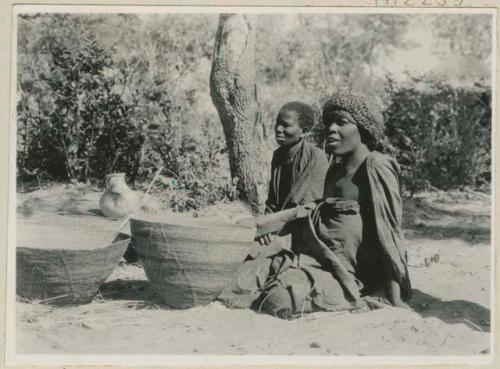 Two women with winnowing baskets and small pot