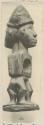 Wooden statuette of two human forms placed back to back with conical hat of latex