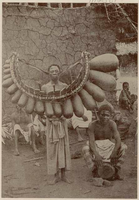 Man with a marimba in front of a hut