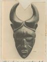 Wooden mask of human face with horns
