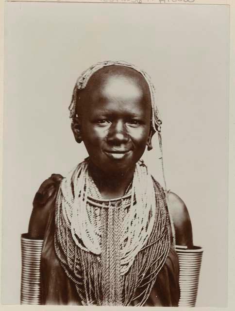 Studio portrait of a girl with bead necklaces and arm rings