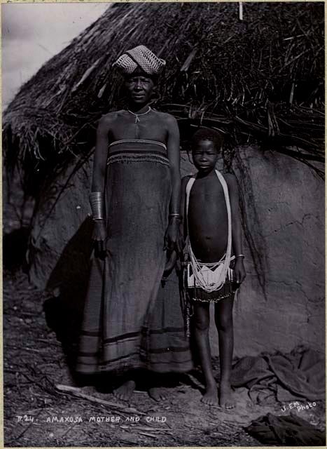 Woman and boy standing in front of a hut