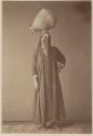 Studio portrait of a woman standing with a water jar on her head