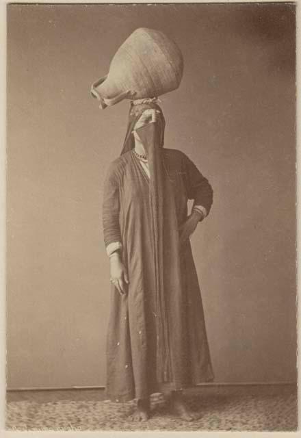 Studio portrait of a woman standing with a water jar on her head