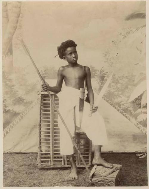 Studio portrait of a boy with a trap and a spear