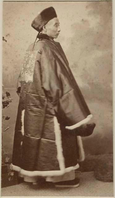 Portrait of man with ornate clothing and fur hat back view