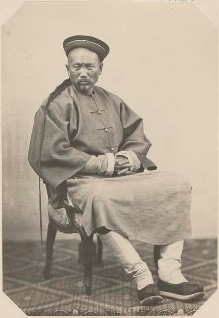 Portrait of Chinese man with long hair sitting and wearing hat