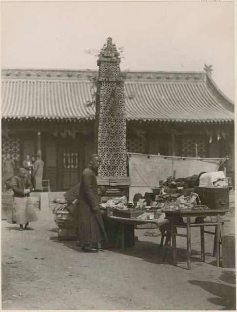 Merchant selling his wares in courtyard of large shop