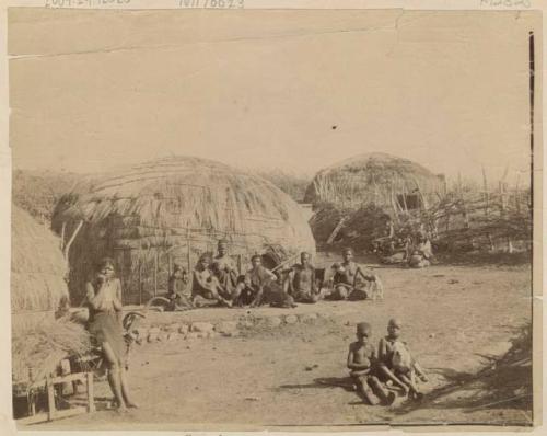 Group of people and two dogs in front of a hut